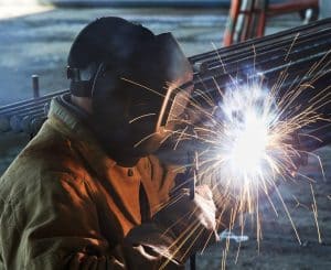 A man in a welding helmet performing welding work.